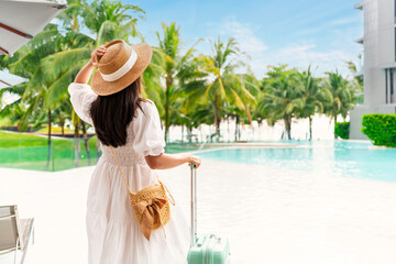 Young woman traveler enjoying a summer vacation at swimming pool in tropical resort near the beach,...