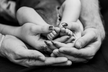 mom and dad holding baby feet black and white photo