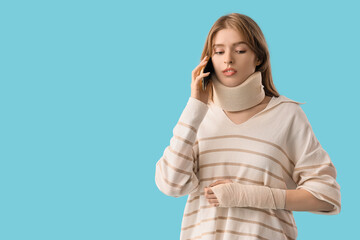 Injured young woman after accident talking by mobile phone on blue background