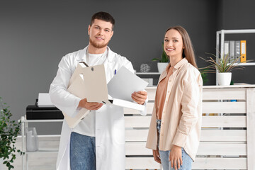Fototapeta premium Male receptionist with folders and patient in clinic