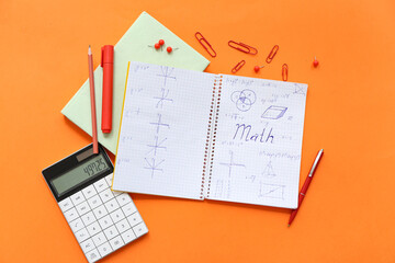 Notebook with calculator, book and school stationery on orange background