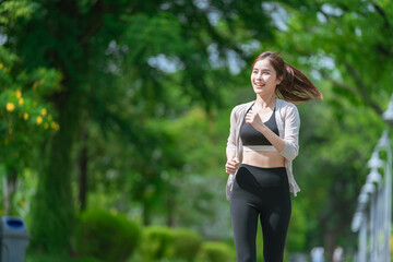 Smiling  Asian woman doing sport exercises running jogging in morning park, skinny fit in sports wear outfit leggings. fitness woman running around in the park.