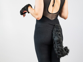 A woman in a cat costume stands with her back showing her tail. Quadrober. 