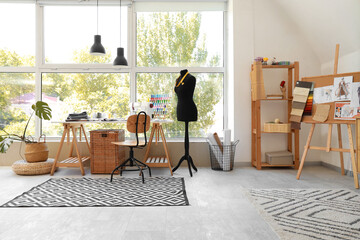 Interior of fashion designer's studio with workplace, shelf unit and mannequin