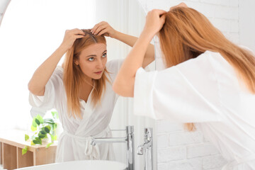 Mature woman with hair loss problem near mirror in bathroom