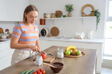 Young woman with chia seed pudding cutting peach in kitchen