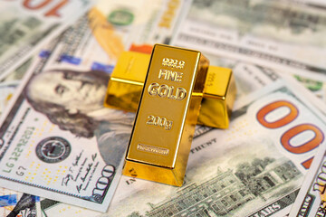 Gold bar and 100-dollar bill on a white background, symbolizing wealth, investment, and financial...