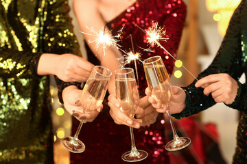 Women in beautiful dresses with Christmas sparklers and champagne at party, closeup