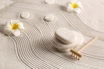 Stones, small rake and tropical flowers on sand with lines. Zen concept