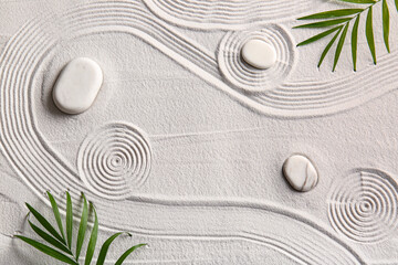 Stones and palm leaves on light sand with lines. Zen concept