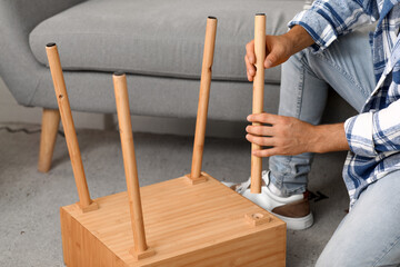 Young man assembling wooden table at home, closeup