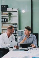 Fototapeta premium Two businessmen working together Analyze financial reports with charts and graphs while using the calculator to calculate budget, income, taxes, business growth. Startup business idea.