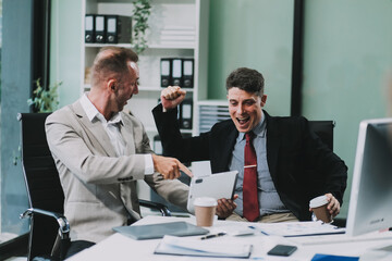 Two happy colleagues with laptop and documents in office