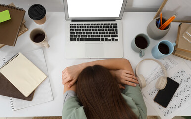Tired female student sleeping at table, top view
