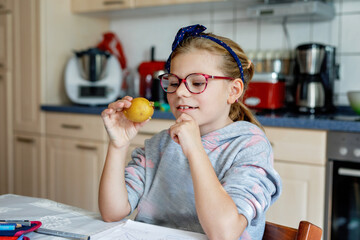 Little young girl with eyeglasses writing in her workbook, doing school homework. Child holding a...