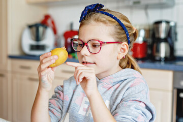 Little young girl with eyeglasses writing in her workbook, doing school homework. Child holding a...