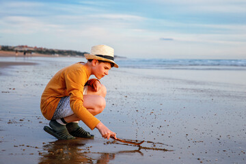 Happy cheerful teenager standing on beach at sunset. happy preteen boy smiling at the camera. Kid on family vacation at the sea.