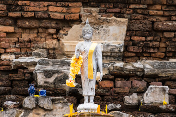 Ayutthaya, Thailand - April, 26, 2024 :Serene Buddha Figure Draped in Yellow Garland, Set Against a...