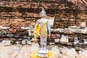 Ayutthaya, Thailand - April, 26, 2024 :Serene Buddha Figure Draped in Yellow Garland, Set Against a...