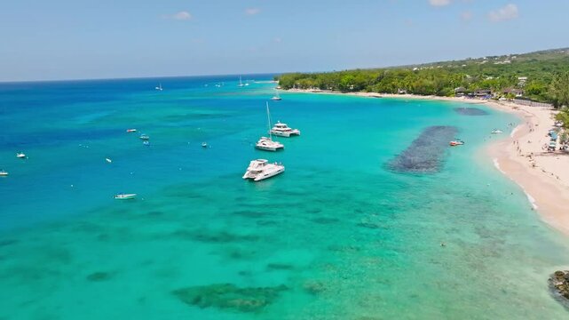 Boats floating near a white sand beach along the turquoise waters of Barbados' west coast