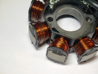 a motorcycle stator, featuring copper windings around iron cores, mounted on a central hub. It’s...