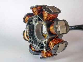 a motorcycle stator, featuring copper windings around iron cores, mounted on a central hub. It’s...