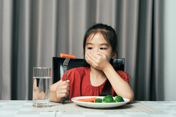 Little cute kid girl refusing to eat healthy vegetables. Children do not like to eat vegetables.