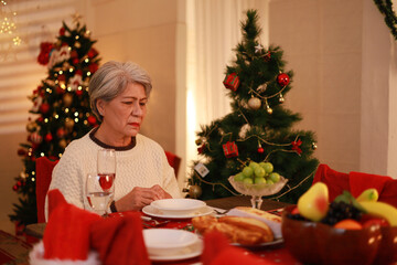 Unhappy elderly woman sitting alone crying on Christmas Eve. Concept of lonely elderly.