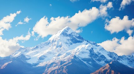 Obraz premium Snowy Mountain Peak Against a Blue Sky with White Clouds