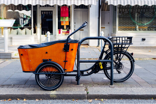 Orange cargo bike parked on a london sidewalk - Powered by Adobe