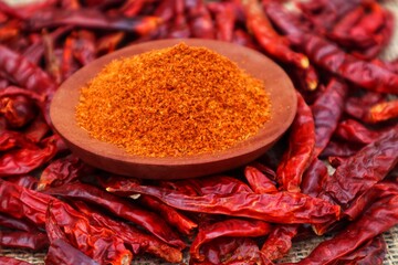 Dried chilies or Capsicum annuum L, piled up and on top there is a wooden bowl containing ground...