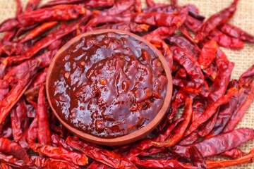 Terasi chili sauce in a wooden bowl and surrounded by dried chilies piled up around it. With a close look.