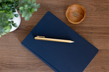 Overhead view of blue book, gold pen, and decor on wooden desk