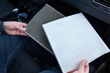 Close up of male hands holding a air filter in a car.