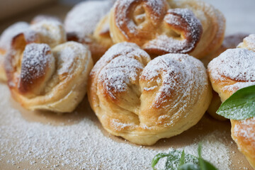 Sweet buns sprinkled with powdered sugar on a wooden table. Selective focus.