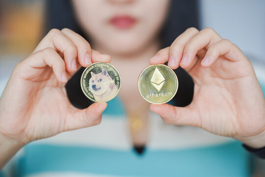 Maesot, Thailand- June 13, 2021:person holds two cryptocurrency coins, one featuring dog and other labeled Ethereum. image captures growing interest in digital currencies and their unique designs