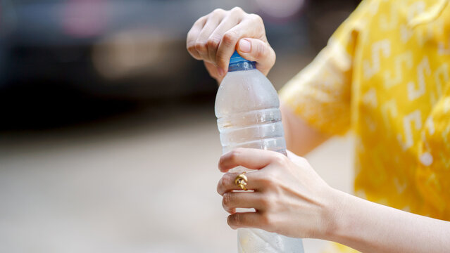 person opening water bottle on warm day, showcasing refreshing hydration