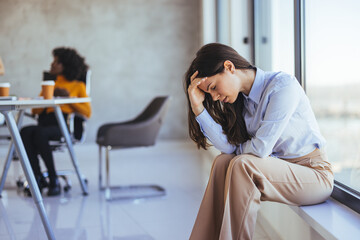 Fototapeta premium Stressed Businesswoman Sitting by Window in Office Environment