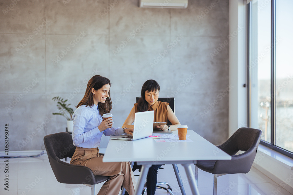 Wall mural two businesswomen collaborating in a modern office setting