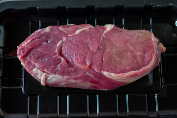 Fresh raw beef in plastic wrap on white background.