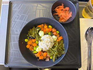A light flight menu - Salad meal a salmon poké bowl with wakame, edamame, carrot, served with...