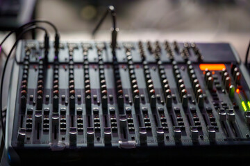 Close-up of an Audio Mixing Console with Faders and Knobs in Low Light