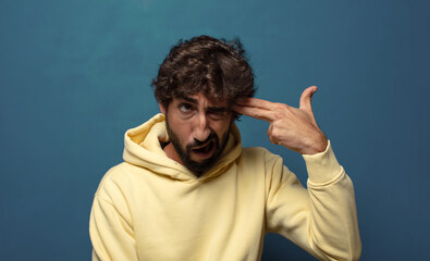 Fototapeta premium looking unhappy and stressed, suicide gesture making gun sign with hand, pointing to head