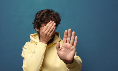 covering face with hand and putting other hand up front to stop camera, refusing photos or pictures