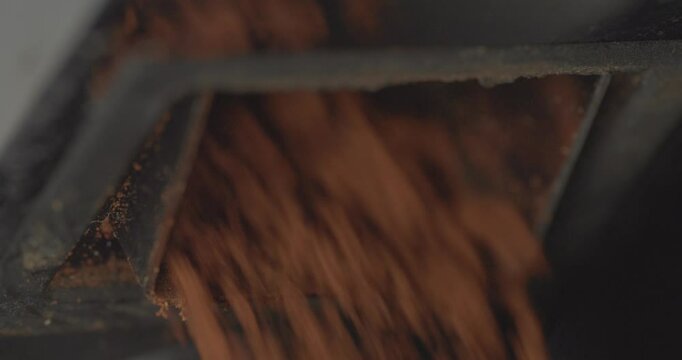 Closeup, macro, super slow motion shot of coffee grounds coming out of a grinder shoot at high speed and stopping abruptly
