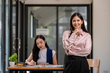 Fototapeta premium Two women are sitting at a desk, one of them is writing