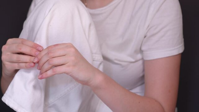 Girl sitting hugging one of her legs, picking at her fingernails. Close up