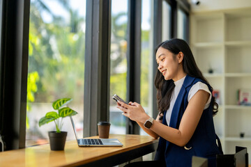 A woman is sitting at a table with a laptop and a cell phone