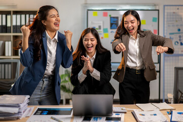 Three women are celebrating in a business setting