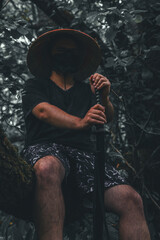 Cosplayer. Vertical. Man with katana sits majestically on tree trunk with katana. Samurai rests...
